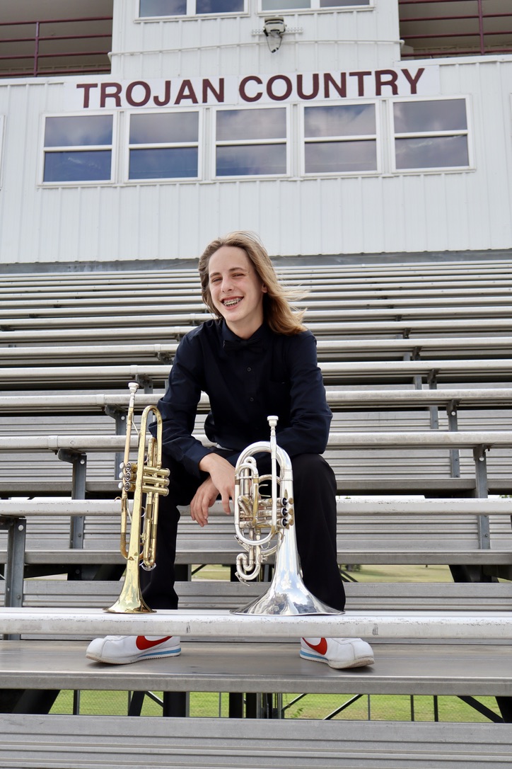Senior seated on bleachers with brass instruments